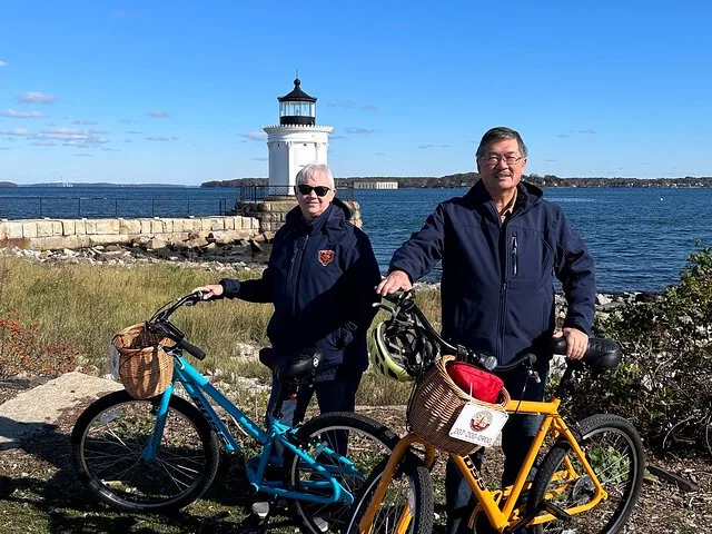 Zwei Personen posieren mit ihren Fahrrädern vor dem Portland Breakwater Lighthouse