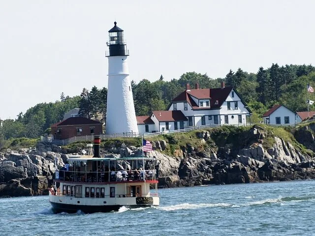 Un bateau d'excursion passant devant le Portland Head Light par une journée ensoleillée