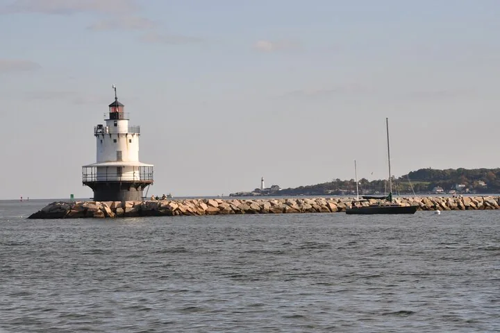 Ein weißer Leuchtturm am Ende eines langen felsigen Wellenbrechers