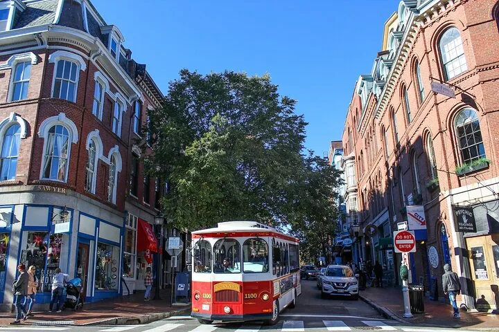 Un bus de type trolley rouge et blanc roulant dans une rue historique de la ville
