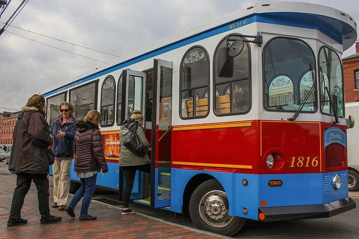 Menschen steigen auf einer Stadtstraße in einen blau-roten Sightseeing-Trolley-Bus ein
