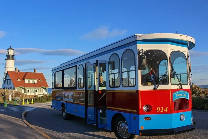 Un bus de type trolley touristique garé près du Portland Head Light par une journée ensoleillée